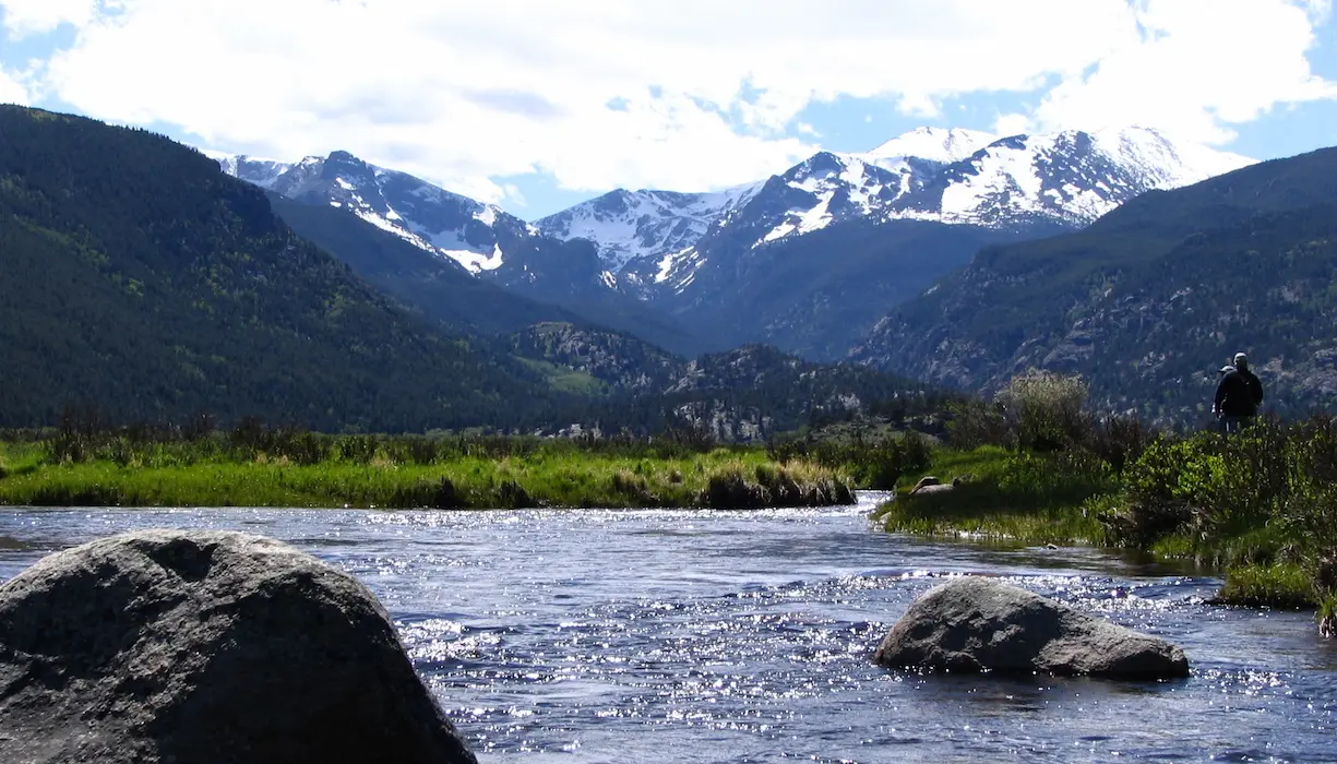 Vista panorámica del Rocky Mountain National Park en Colorado, con río y montañas nevadas al fondo